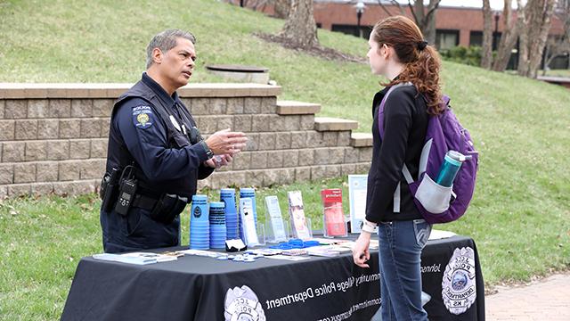 Student speaking with a police officer at a table during Cav Craze